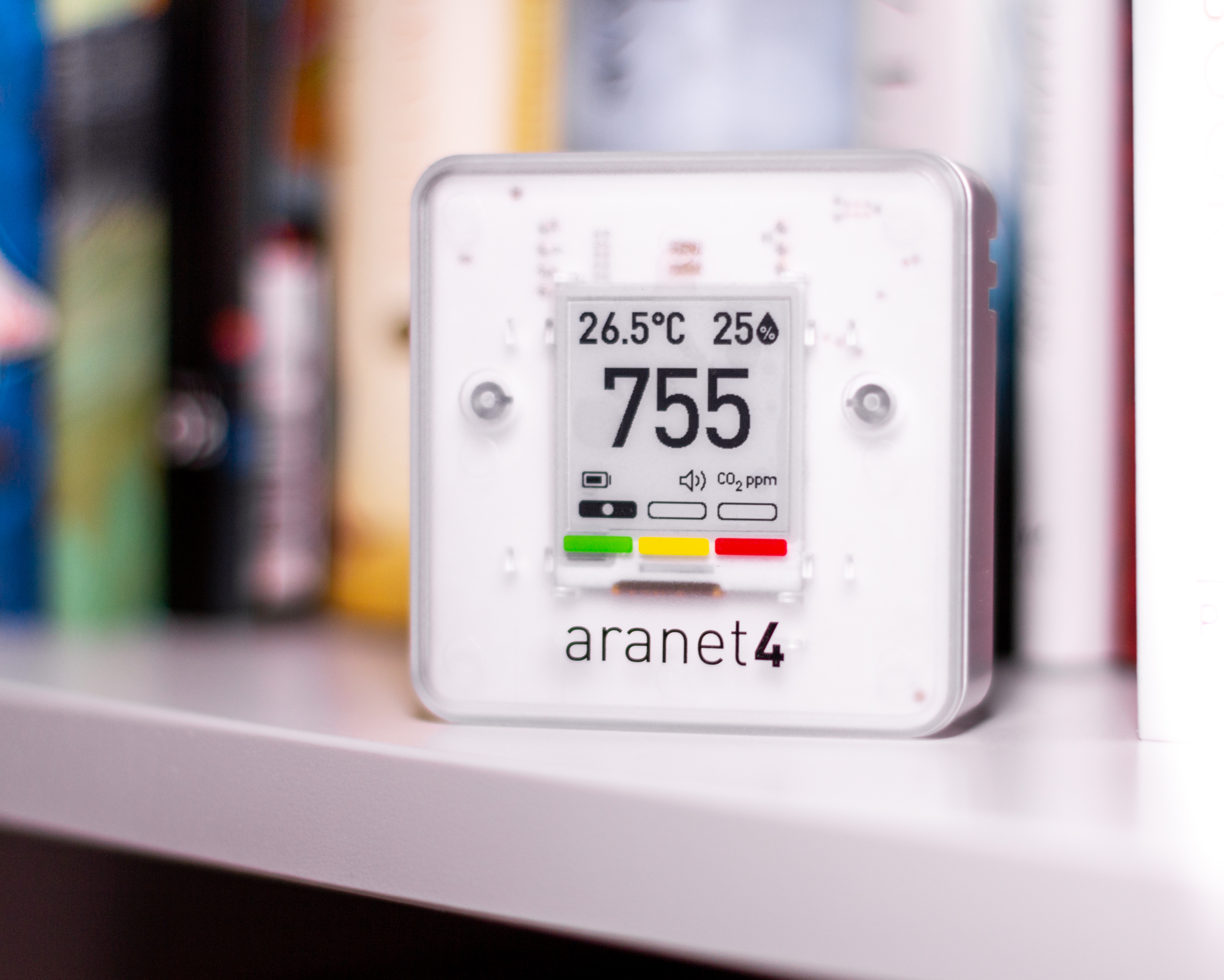An Aranet4 Home Indoor Air Quality Monitor sits on a shelf. It shows a ‘safe’ reading of 775 ppm, as well as temperature and relative humidity readings.